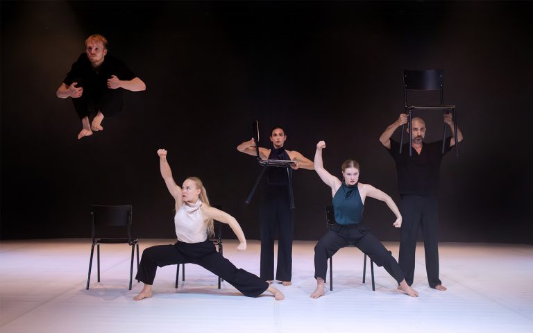 Groupe de danseurs sur sc&egrave;ne avec des chaises 
