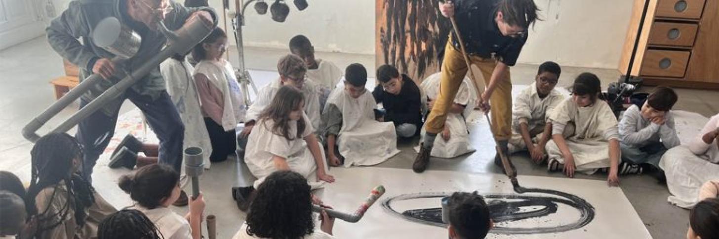 Personne qui peind avec un instrument g&eacute;ant entour&eacute; d'enfants