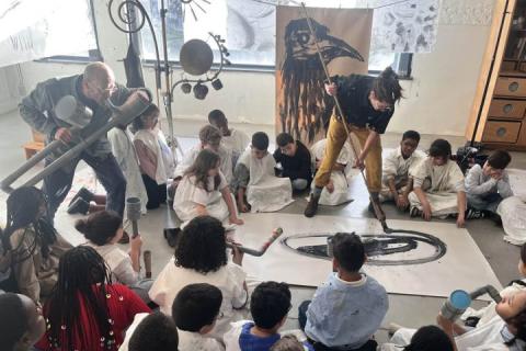 Personne qui peind avec un instrument g&eacute;ant entour&eacute; d'enfants